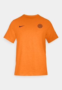 Camiseta Nike naranja con cuello redondo, mangas cortas y un logo redondo de club en negro en el pecho. Material de algodón suave con una textura lisa.