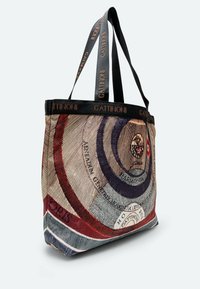 Borsa a tracolla con motivi circolari concentrici colorati, realizzata in tessuto con manici neri, e dettagli del logo lungo il bordo superiore.
