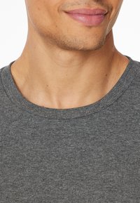 T-shirt gris texturé à col ras du cou avec un col côtelé, présentant un motif chiné subtil et fabriqué en tissu doux et léger.