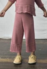 Roze gebreide outfit met cropped pants met een scalloped zoom en een bijpassend top. Zachte textuur; gecombineerd met beige espadrille schoenen.