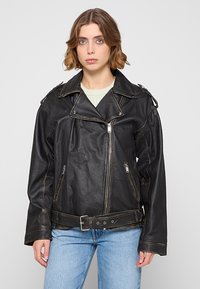 Czarna skórzana kurtka motocyklowa z wysokim kołnierzem, srebrnymi zamkami błyskawicznymi i akcentami paska; charakteryzuje się luźnym krojem i widocznym przeszyciem.