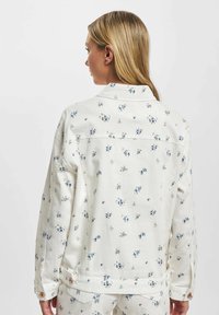 Denimjakke med blomsterdesign i off-white, med små blå blomster, knappepryd, krage og en avslappet passform.