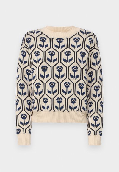 Pull crème avec un motif floral géométrique bleu marine, des poignets et un ourlet côtelés, des manches courtes et un col rond.
