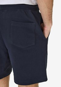 Navyblå shorts i mjukt bomull, med en bakficka i rektangulär form och synliga sömnadsdetaljer.