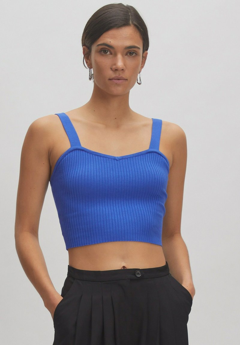 Blauwe geribbelde crop top met brede bandjes en een sweetheart halslijn, met een aansluitend ontwerp en een gladde textuur. Draagt met zwarte broeken.