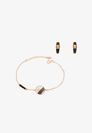 Złota bransoletka z łańcuszkiem z okrągłym czarno-złotym geometrycznym zawieszką oraz pasujące małe czarno-złote kolczyki koła.