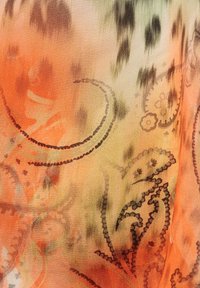 Fließender Stoff mit einem Farbverlauf von Orange- zu Grüntönen, der komplizierte schwarze Paisleymuster und eine weiche, strukturierte Oberfläche aufweist.