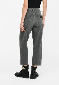 Jeans a vita alta e gamba larga in denim grigio lucido con finitura texturizzata, dotati di due tasche posteriori e un'etichetta vicino alla vita.