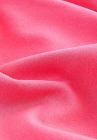 Textil med en livlig korallfärg, mjuk textur och slät yta med subtila variationer i nyans och glans från veck.
