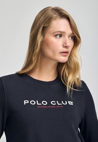 Felpa blu navy con collo a giro, caratterizzata da un logo "POLO CLUB" bianco e rosso e il testo "ESTABLISHED 2012" sul davanti. Texture morbida.