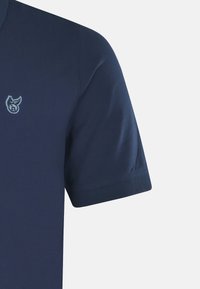 Mörkblå pikétröja med korta ärmar, texturerad tyg och en ljusblå broderad logotyp på bröstet, med en klassisk kragdesign.