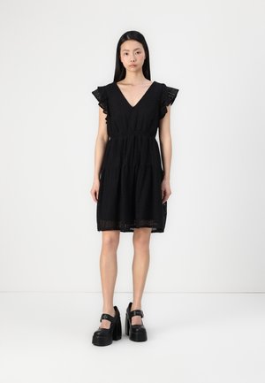 Black dress with a V-neck, short ruffled sleeves, and a pleated design. Features lace detailing and an elastic waist for fit. Black platform shoes.