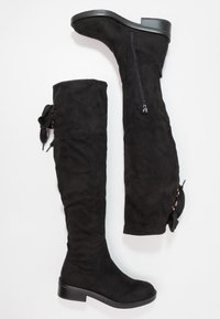 Paire de bottes montantes en daim noir avec talons bas, fermetures éclair latérales et lacets décoratifs en ruban à l'arrière.
