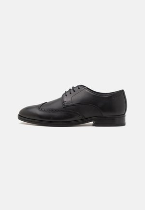 Chaussure habillée en cuir noir avec une texture lisse et des détails perforés. Elle possède un design à lacets et un talon bas et solide.