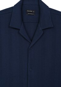Camicia a maniche corte blu navy realizzata in tessuto a trama a rete. Presenta un colletto classico e due bottoni frontali per la chiusura. Vestibilità rilassata.