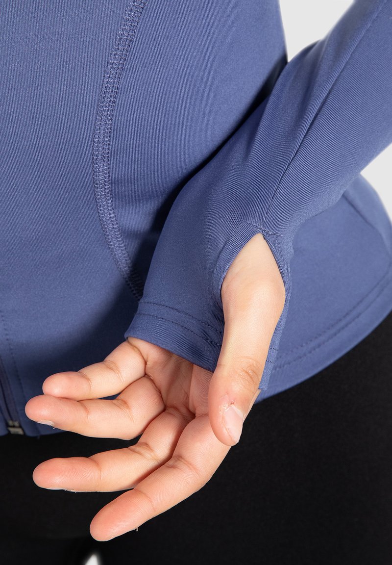 Camisa de manga larga de color navy con orificios para los pulgares, que presenta una textura de tela suave y costuras planas. Manos posicionadas para una mejor visibilidad de los detalles.