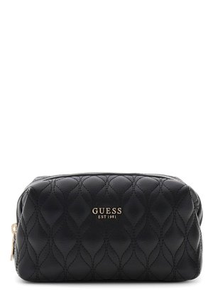 Pochette Guess noire matelassée avec fermeture éclair dorée et logo "GUESS EST 1981" embossé à l’avant, présentée sur fond blanc.