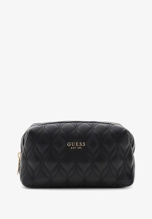 Pochette Guess noire matelassée avec fermeture éclair dorée et logo "GUESS EST 1981" embossé à l’avant, présentée sur fond blanc.