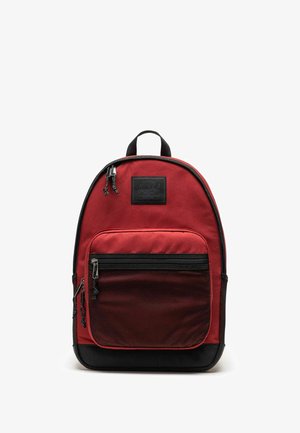 Sac à dos rouge et noir avec poche zippée à l'avant, deux fermetures éclair sur le compartiment principal et une poignée supérieure.