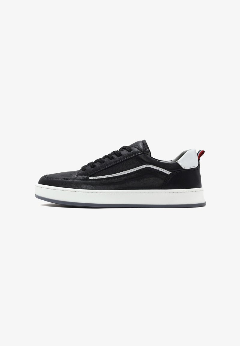 Czarne skórzane sneakersy z tonalnym przeszyciem, białą podeszwą środkową oraz kontrastowymi szarymi i czerwonymi akcentami na pięcie. Posiadają zaokrąglony czubek i sznurowaną konstrukcję.