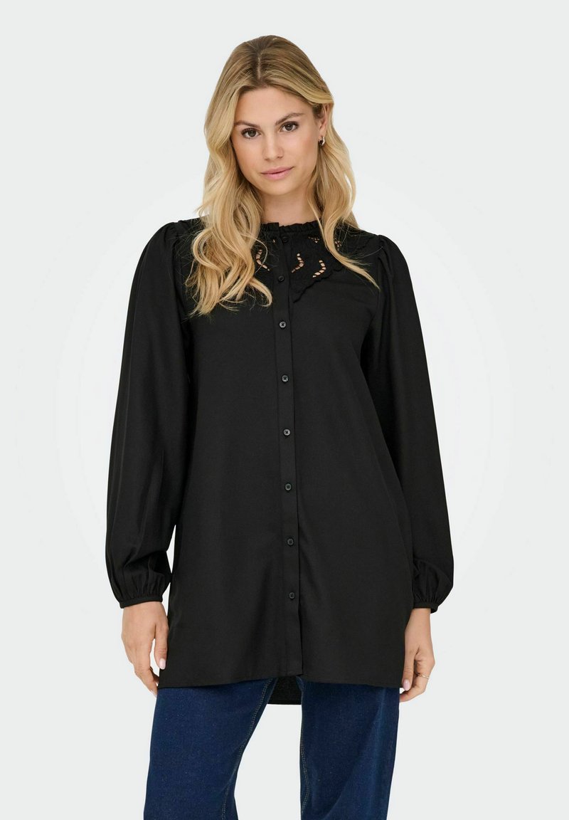 Blouse noire à manches longues avec fermeture à boutons, dotée d'un col à volants et d'une broderie discrète. Tissu doux et lisse avec une coupe décontractée.