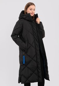 Zwarte geblokte lange jas met een capuchon, voorzien van een blauwe rits en een decoratieve blauwe franjer. Gemaakt van een glad, glanzend materiaal.
