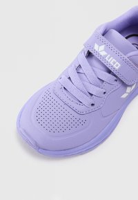 Chaussure de sport violette avec des détails en maille, des lacets en tissu et une sangle à boucle. Présente une semelle texturée et un marquage minimal en blanc.
