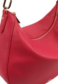 Rode leren schoudertas met een gladde textuur, gebogen ontwerp, gouden ritsdetails en een gouden hardware accent voor de riembevestiging.