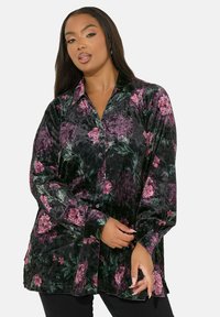La camicia nera a fiori presenta una texture morbida con motivi floreali rosa e verdi, maniche lunghe e una vestibilità rilassata.
