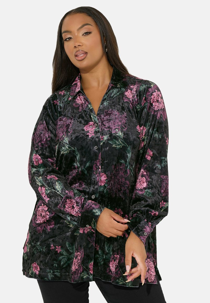 La camicia nera a fiori presenta una texture morbida con motivi floreali rosa e verdi, maniche lunghe e una vestibilità rilassata.