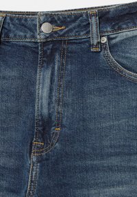 Približen posnetek pasu modrih denim kavbojk z gumbom, zanko za pas, sprednjim žepom in vidnim rumenim šivom.