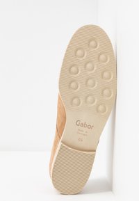 Suède tan schoenen met een beige rubberen zool, voorzien van een gestructureerde grip en ronde studs. Gemarkeerd met "Gabor, Made in Portugal, 4½."