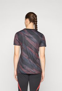 Zwart T-shirt met korte mouwen met een abstract gestreept patroon in rood en grijs, voorzien van een ronde halslijn en een slim fit silhouet.
