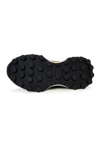 Semelle extérieure en caoutchouc noir d'une chaussure avec de grosses pastilles rondes pour une meilleure adhérence sur diverses surfaces.