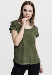 T-shirt verde oliva a maniche corte con scollatura ampia e risvolti. Tessuto morbido e orlo leggermente arrotondato.
