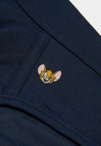 Námořnická bavlněná látka s hladkou texturou, zdobená malou vyšitou kreslenou postavičkou. Šití podrobně umístěné podél okrajů.