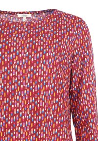 Lang�ärmliges Oberteil aus weichem Stoff, mit einem maronfarbenen Hintergrund und bunten, länglichen Punkten in Tönen von Pink, Blau und Gelb.