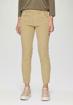 Beige corduroy broek in slim fit, met voorzakken, riemlussen en een textuurstof. Gecombineerd met lichtgekleurde schoenen.