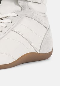 Vit sneakersko med en kombination av slätt läder och mocka, rund tå, snörning och sula i gummiblandning för bra grepp.