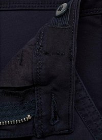 Navy stof close-up met een knoop, stikseldetails en een ritszak met metalen tanden. Glad oppervlak met gestructureerde vormen.