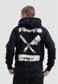 Felpa nera con cappuccio caratterizzata da un grande design a pennellate grafiche in rosa e bianco sul retro. Tessuto morbido con una vestibilità comoda e tasca a marsupio.