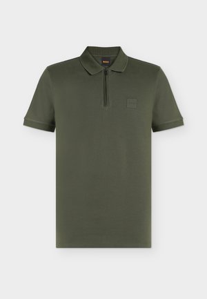 Polo manches courtes vert olive avec col, fermeture éclair quart de zip et petit écusson carré avec logo sur la poitrine gauche.