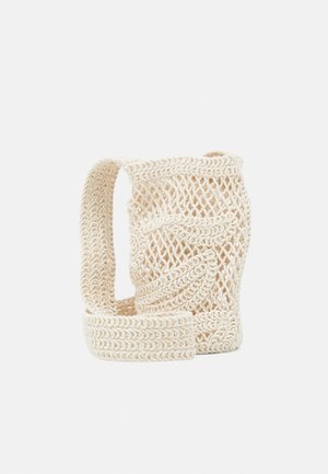Sac filet crocheté couleur crème avec une bandoulière épaisse, présentant un tissage ouvert et des motifs complexes en forme de feuilles.