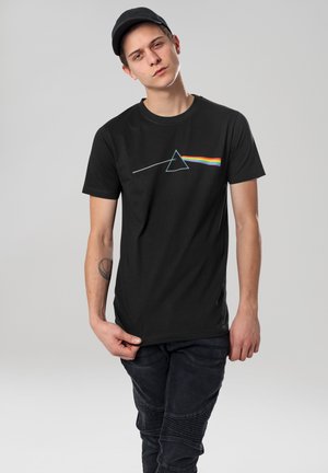 T-shirt noir avec un graphique représentant un triangle et des rayures arc-en-ciel. Fait en coton, avec des manches courtes et un col rond.