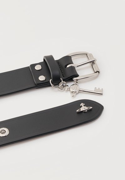 Μαύρη δερμάτινη ζώνη με ασημί αγκράφα, γούρι σε σχήμα κλειδιού κρεμασμένο κοντά στην αγκράφα και μικρό ασημί λογότυπο σε σχήμα σφαίρας στην άκρη της ζώνης.