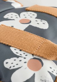 Floral-patterned fabric in gray with white flowers and peach accents. Features a textured orange strap with woven detail for grip.