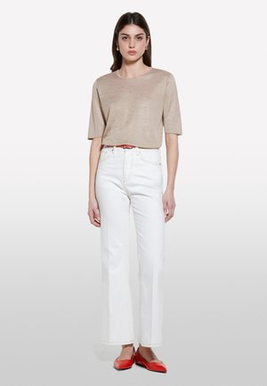 Top beige a maniche corte, jeans bianchi a gamba larga, scarpe rosse. L'outfit include una cintura arancione e una texture semplice senza motivi o dettagli.