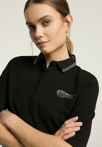 Czarna koszulka polo z kołnierzykiem w szare paski. Logo na piersiach z napisem "Diverse ExtremeTeam.com." Bawełnowy materiał, dopasowany krój.