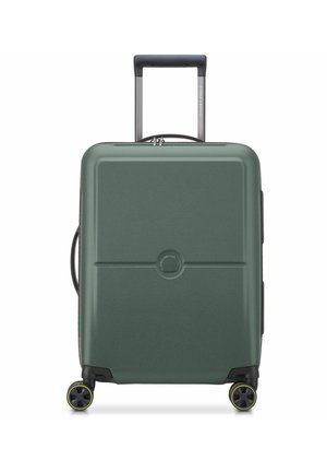 Valise rigide verte avec quatre roulettes pivotantes bordées de jaune et une poignée télescopique noire allongée, vue de face sur fond blanc.