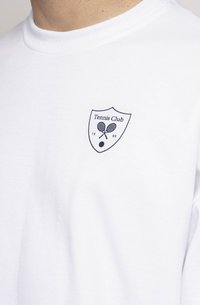 Camiseta branca de algodão com um pequeno logo em azul marinho "Tennis Club" com raquetes cruzadas e uma bola, situado na área do lado esquerdo do peito.